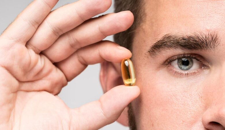 Hombre mostrando pequeña cápsula de suplementos