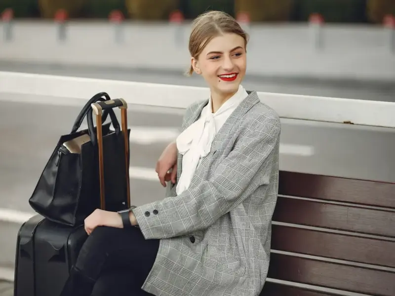 Mujer joven sentada en banco con maletas
