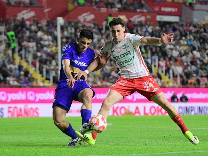 Jugador de Necaxa contra jugador de Pumas en campo de fútbol
